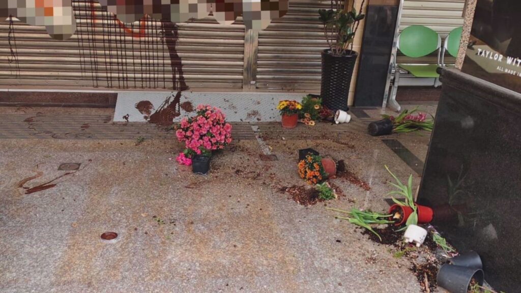 楠梓區德民路店家鐵捲門遭潘女噴漆，門口盆栽被砸毀，碎片與泥土散落一地。(圖：記者李佳龍／翻攝)